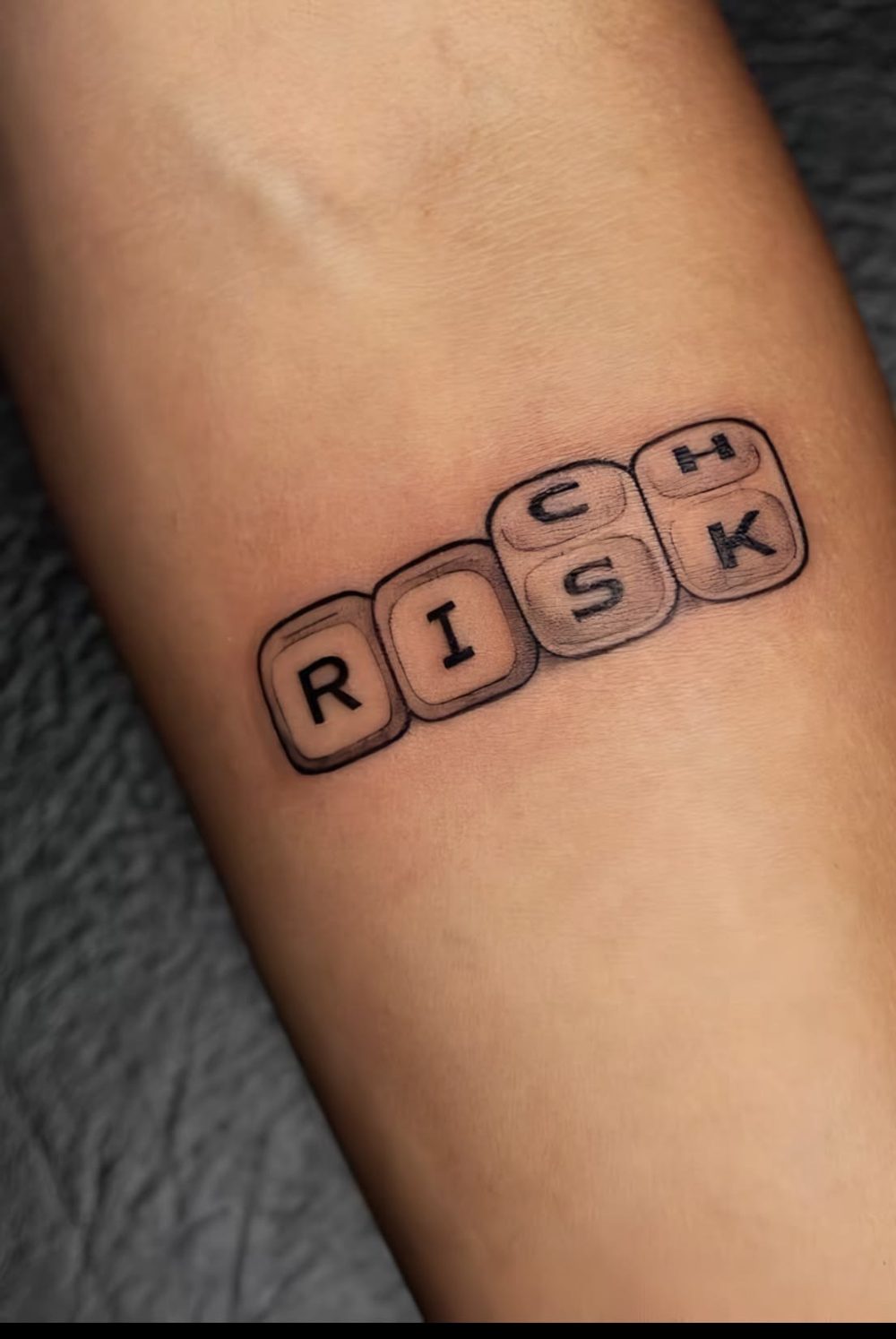 RISK dice lettering tattoo, forearm
